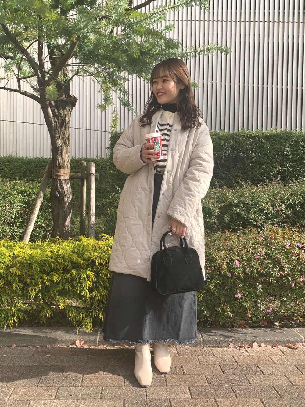 ホワイト系のカーディガン/ボレロ、ブラック系のハンドバッグ、ブラック系のデニムスカートを着用したレディースの冬コーディネートの3枚目の写真