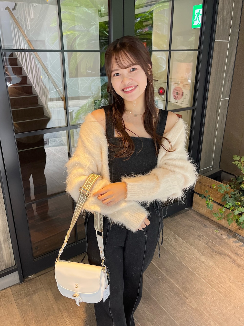 ホワイト系のショルダーバッグ、ホワイト系のカーディガン/ボレロ、ブラック系のサロペット/オーバーオールを着用したレディースの夏コーディネートの2枚目の写真