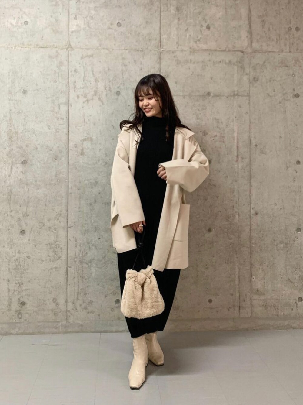 ブラック系のニット/セーター、ホワイト系のチェスターコート、ホワイト系のショルダーバッグを着用したレディースの冬コーディネートの2枚目の写真