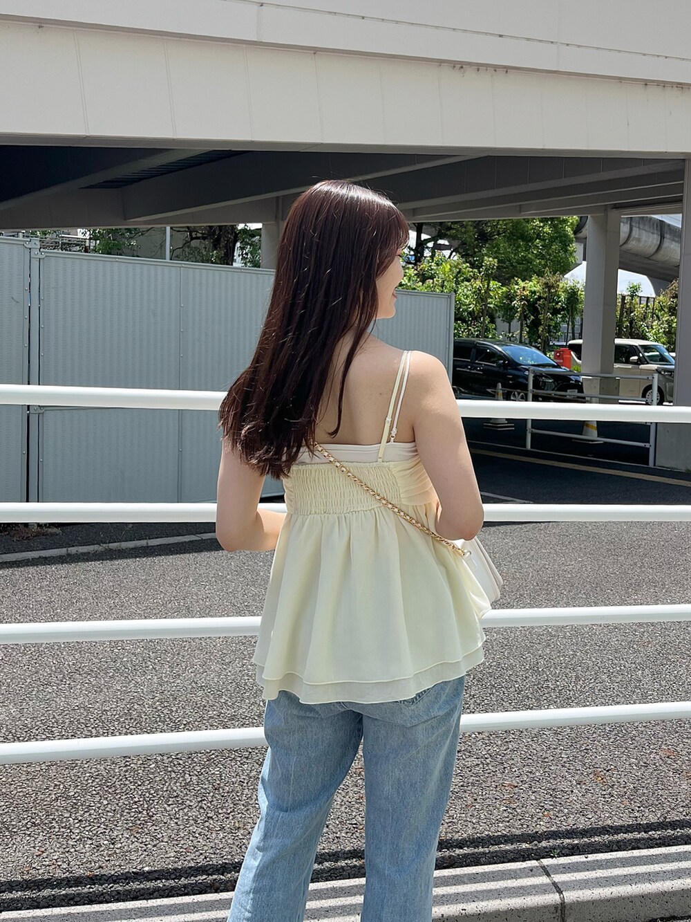 ブルー系のデニムパンツ、ホワイト系のサンダル、ホワイト系のショルダーバッグを着用したレディースの春コーディネートの3枚目の写真