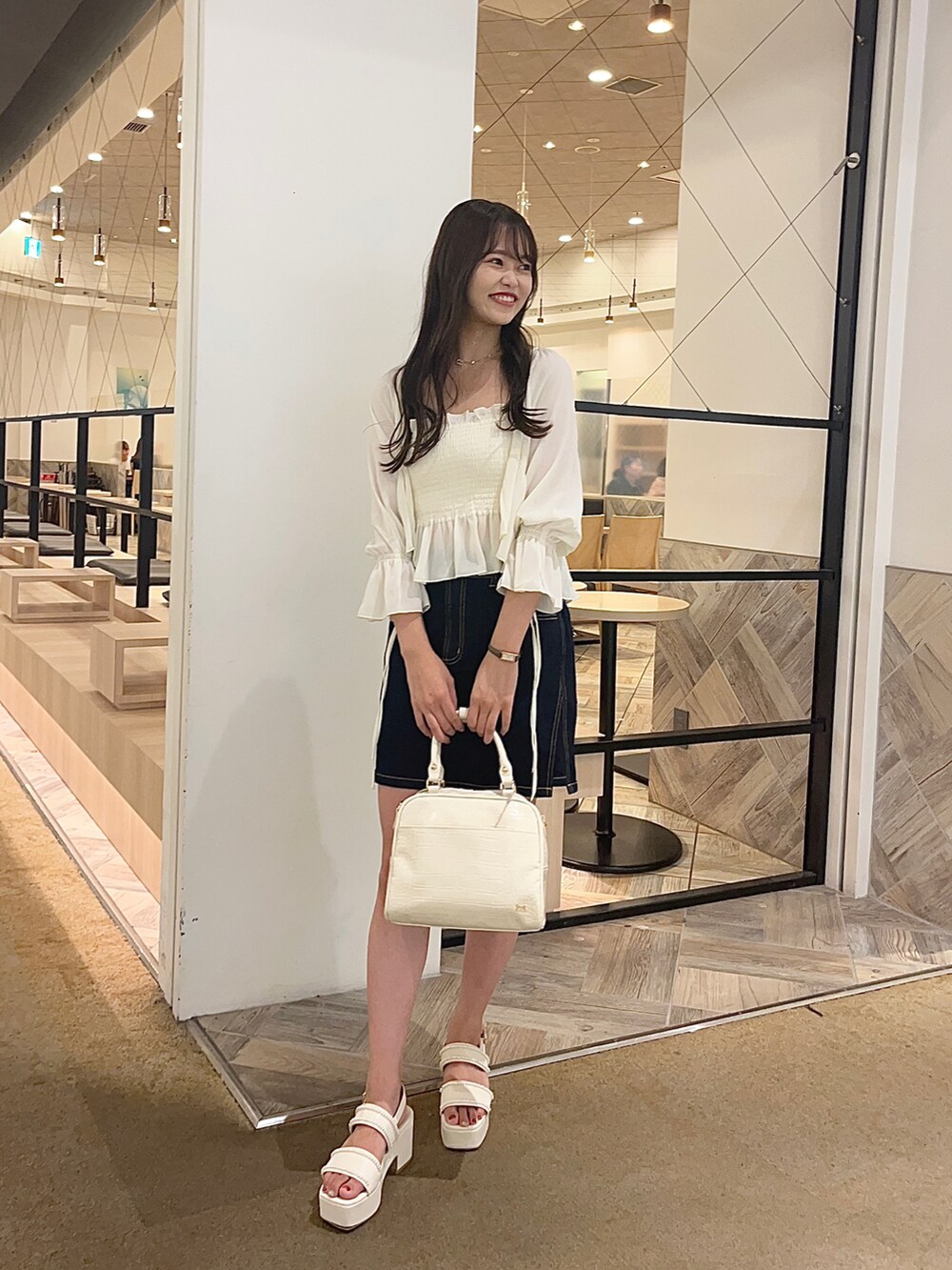 ホワイト系のシャツ/ブラウス、ブルー系のデニムスカート、ホワイト系のボストンバッグを着用したレディースの夏コーディネートの2枚目の写真