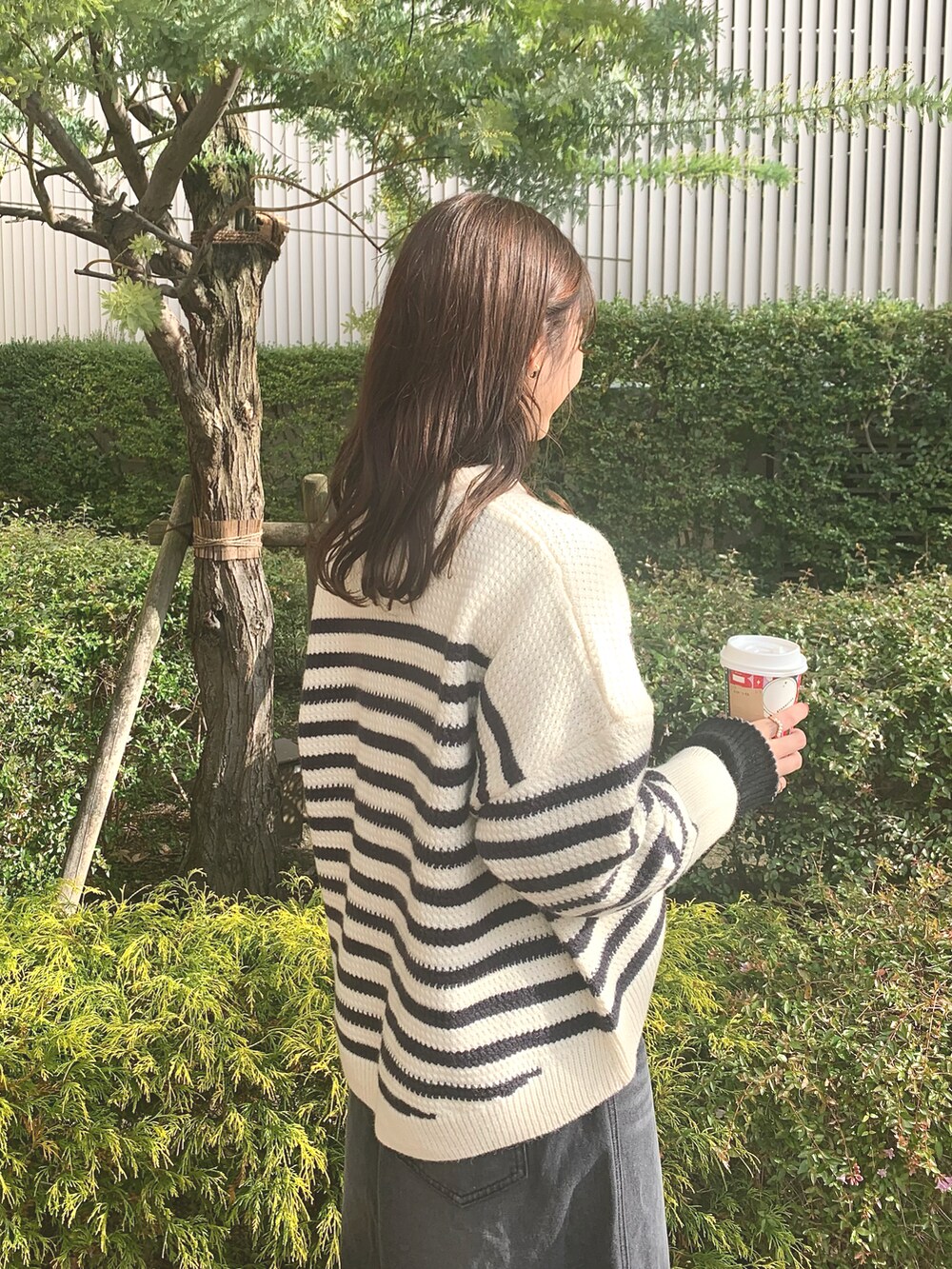 ホワイト系のカーディガン/ボレロ、ブラック系のハンドバッグ、ブラック系のデニムスカートを着用したレディースの冬コーディネートの4枚目の写真