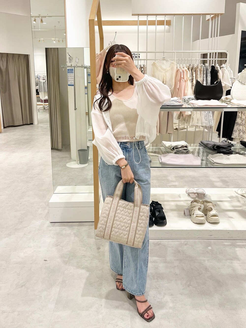 ベージュ系のショルダーバッグ、ブルー系のデニムパンツ、ピンク系のタンクトップを着用したレディースの夏コーディネートの2枚目の写真