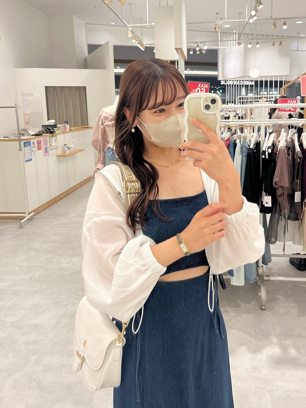 ブルー系のワンピース、ブラウン系のショルダーバッグ、ホワイト系のマウンテンパーカーを着用したレディースの夏コーディネートの2枚目の写真