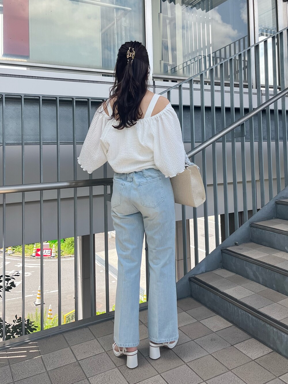 ブルー系のデニムパンツ、ピンク系のショルダーバッグ、ホワイト系のアンサンブルを着用したレディースの春コーディネートの3枚目の写真