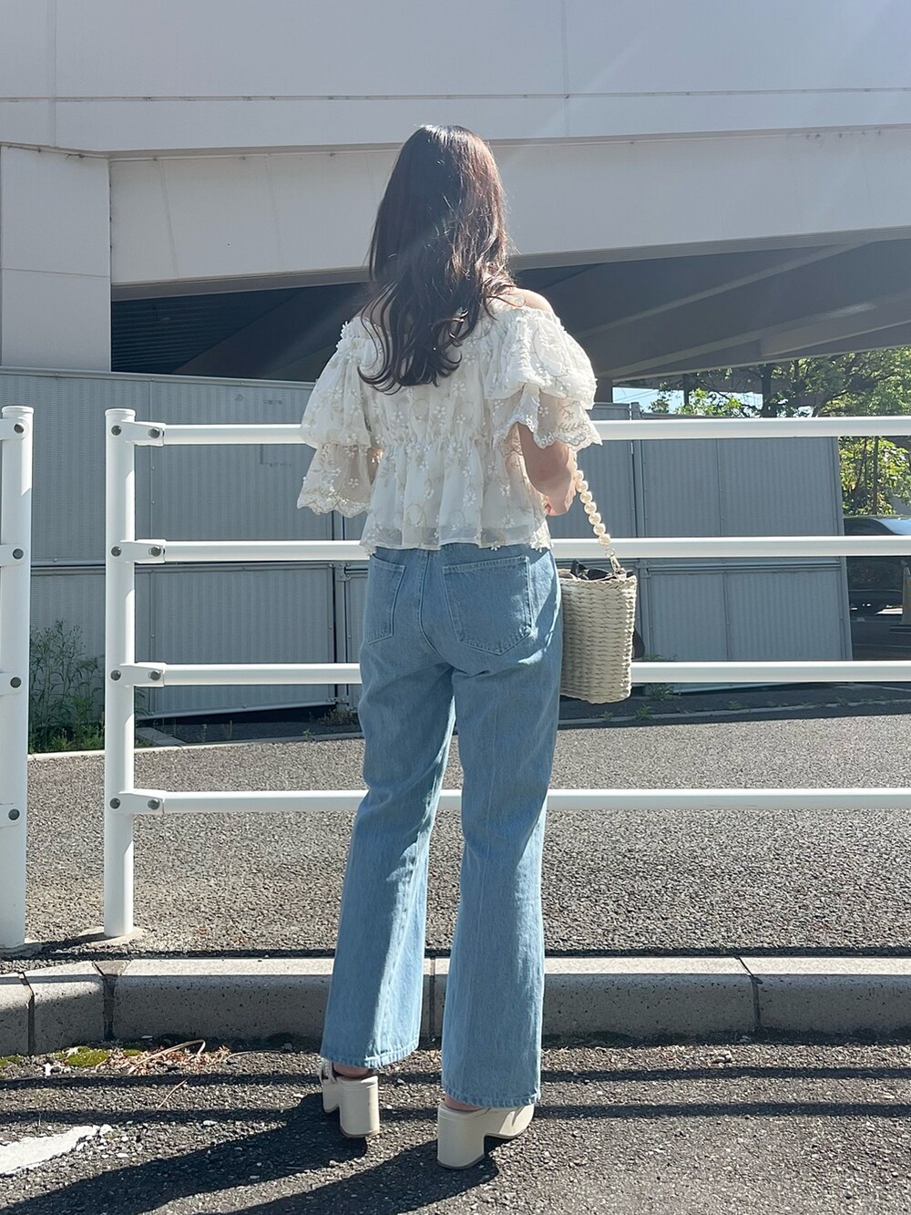 ブルー系のデニムパンツ、ブラック系のかごバッグ、ホワイト系のシャツ/ブラウスを着用したレディースの春コーディネートの3枚目の写真