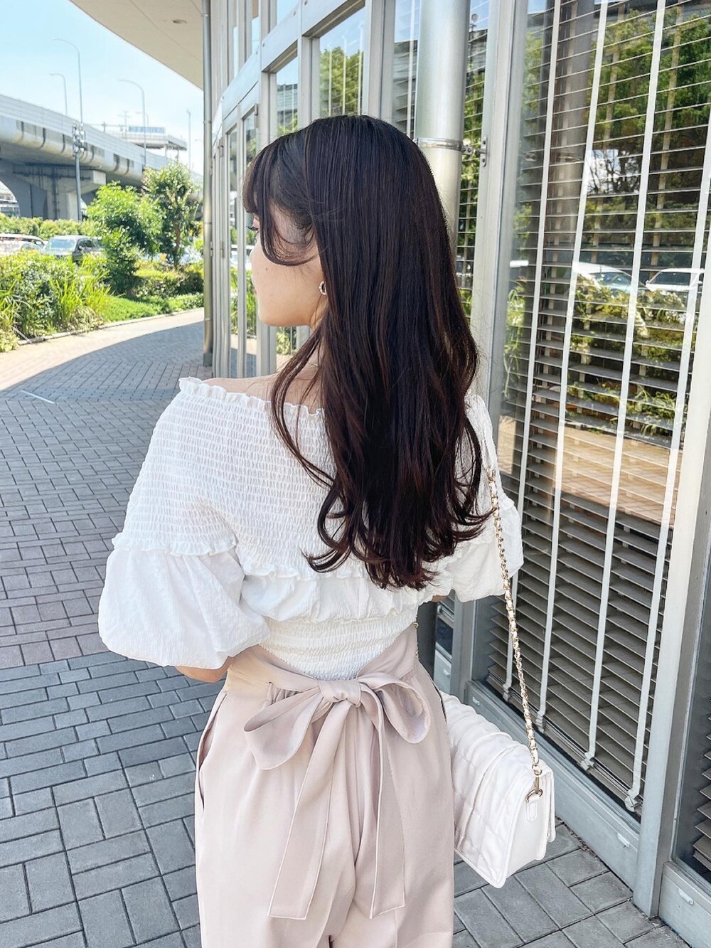 パープル系のスラックス、ホワイト系のサンダル、ホワイト系のショルダーバッグを着用したレディースの夏コーディネートの3枚目の写真