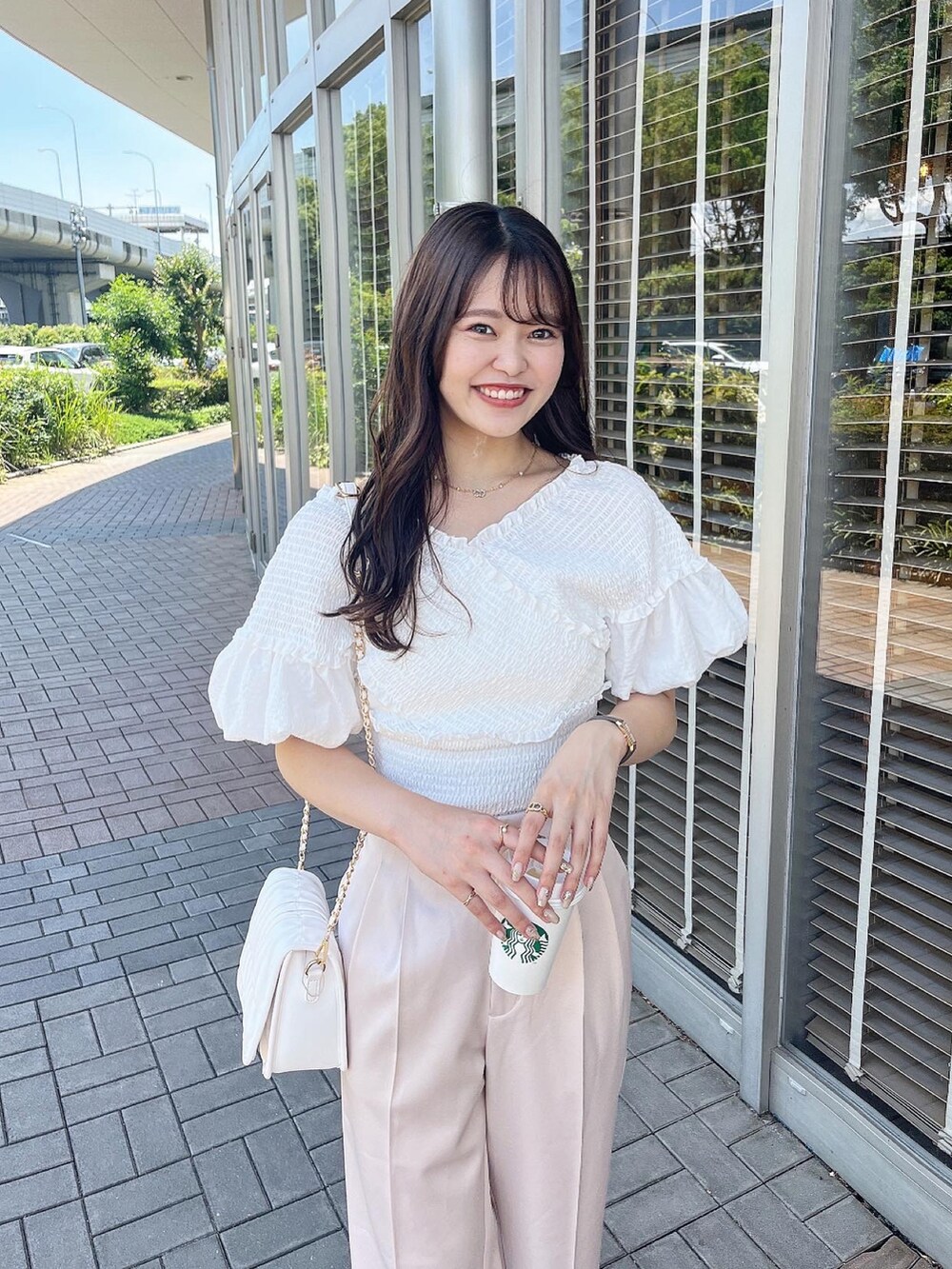 パープル系のスラックス、ホワイト系のサンダル、ホワイト系のショルダーバッグを着用したレディースの夏コーディネートの2枚目の写真