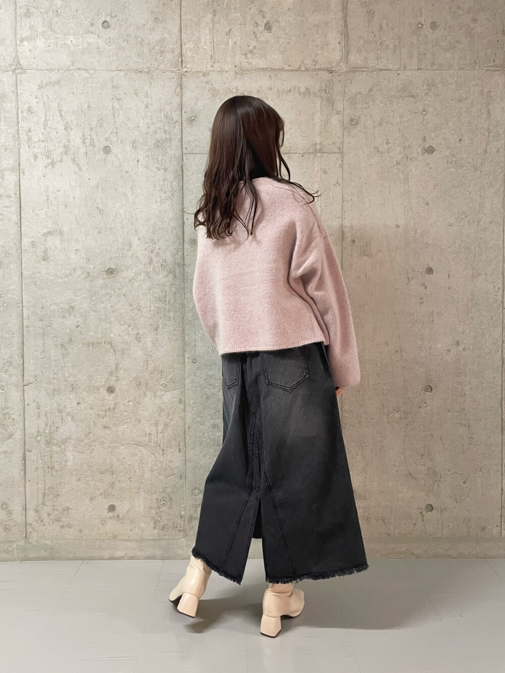 グリーン系のニット/セーター、ブラック系のデニムスカート、ホワイト系のブーツを着用したレディースの冬コーディネートの3枚目の写真