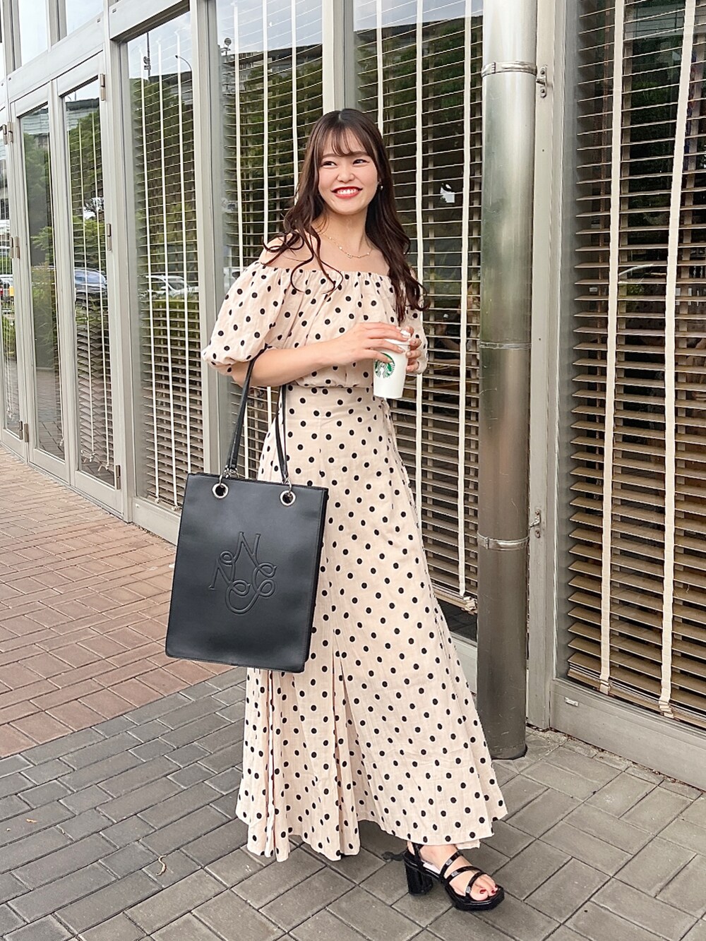 ホワイト系のトートバッグ、ブラック系のサンダル、その他のスカートを着用したレディースの夏コーディネートの2枚目の写真