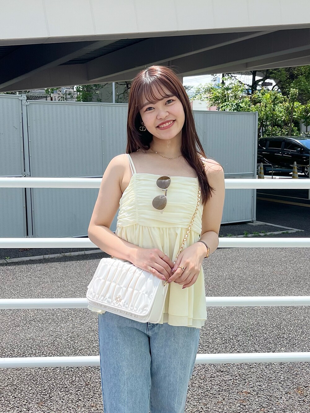 ブルー系のデニムパンツ、ホワイト系のサンダル、ホワイト系のショルダーバッグを着用したレディースの春コーディネートの2枚目の写真