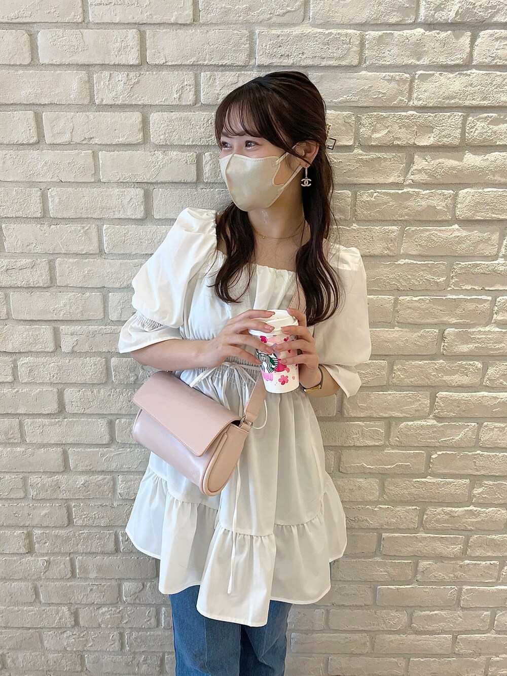 ブルー系のデニムパンツ、ホワイト系のサンダル、ホワイト系のチュニックを着用したレディースの春コーディネートの2枚目の写真