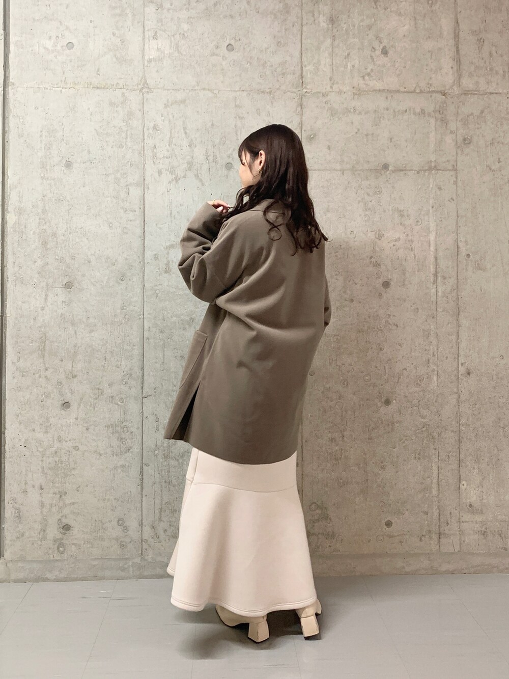 ホワイト系のチェスターコート、ピンク系のニット/セーター、ベージュ系のスカートを着用したレディースの冬コーディネートの3枚目の写真