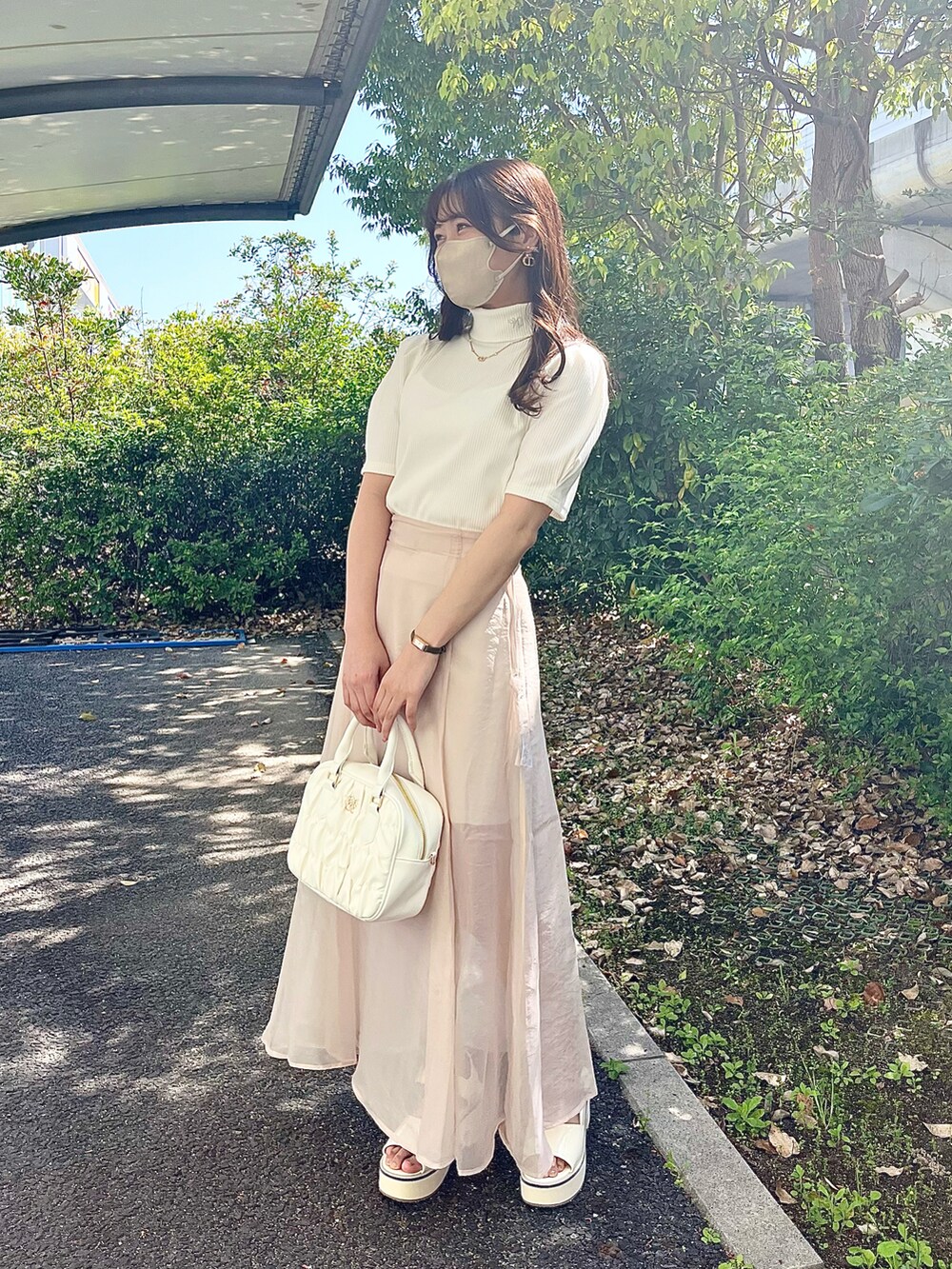 ピンク系のボストンバッグ、ホワイト系のTシャツ/カットソー、ベージュ系のスカートを着用したレディースの春コーディネートの2枚目の写真