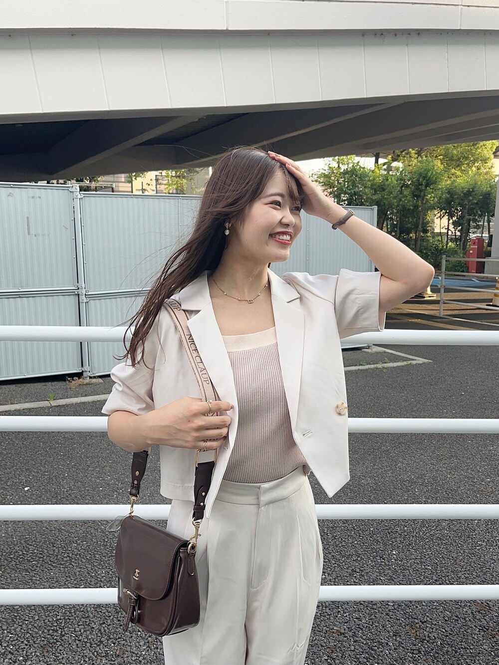 ベージュ系のスラックス、ピンク系のタンクトップ、ブラウン系のショルダーバッグを着用したレディースの夏コーディネートの2枚目の写真