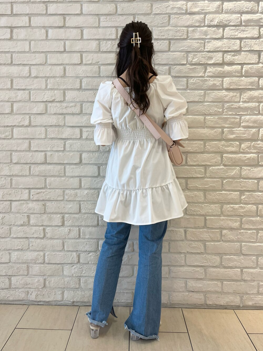 ブルー系のデニムパンツ、ホワイト系のサンダル、ホワイト系のチュニックを着用したレディースの春コーディネートの3枚目の写真