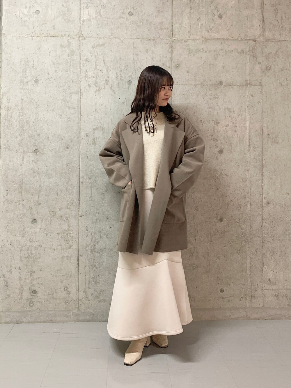 ホワイト系のチェスターコート、ピンク系のニット/セーター、ベージュ系のスカートを着用したレディースの冬コーディネートの2枚目の写真