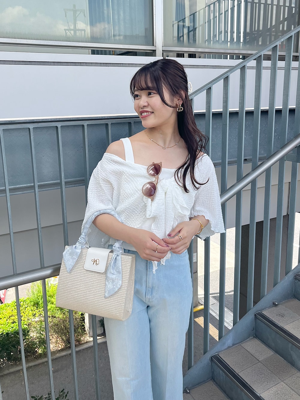 ブルー系のデニムパンツ、ピンク系のショルダーバッグ、ホワイト系のアンサンブルを着用したレディースの春コーディネートの2枚目の写真