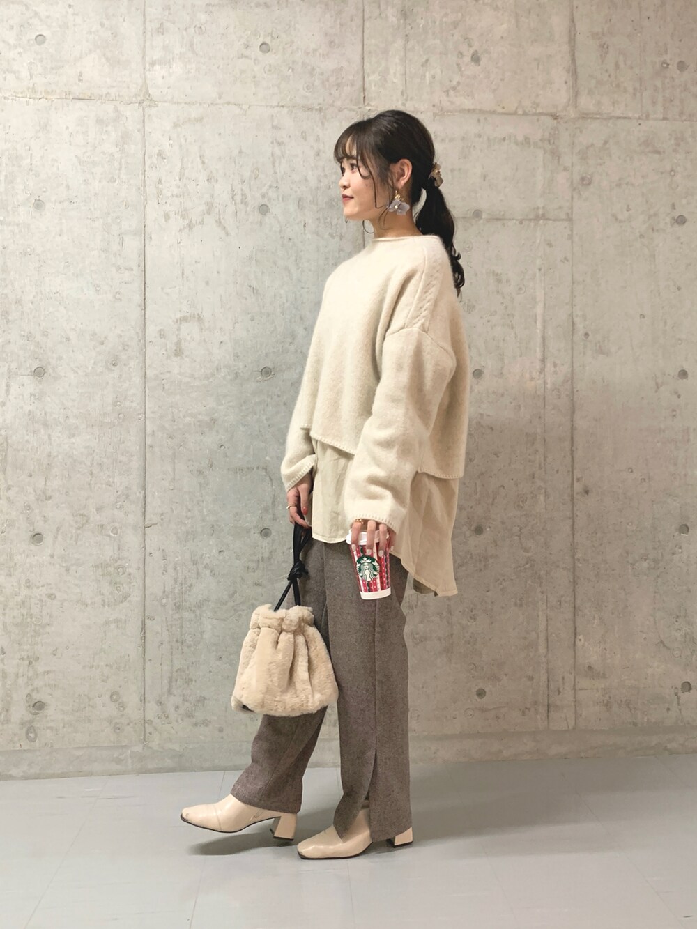 ホワイト系のニット/セーター、ホワイト系のブーツ、ブラウン系のスラックスを着用したレディースの冬コーディネートの2枚目の写真