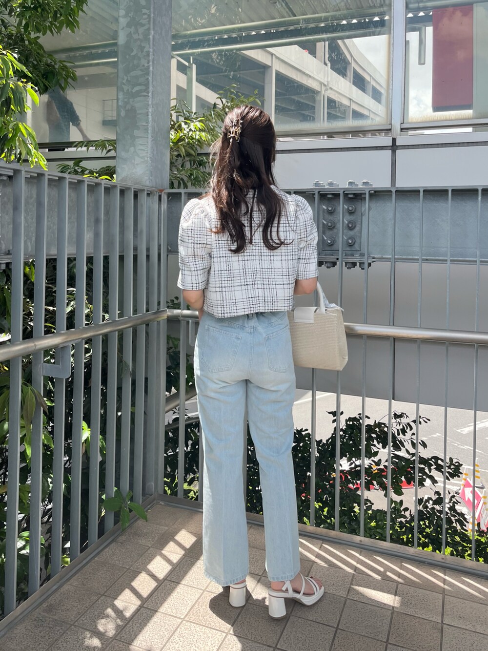 ピンク系のショルダーバッグ、ピンク系のノーカラージャケット、ブルー系のデニムパンツを着用したレディースの春コーディネートの2枚目の写真