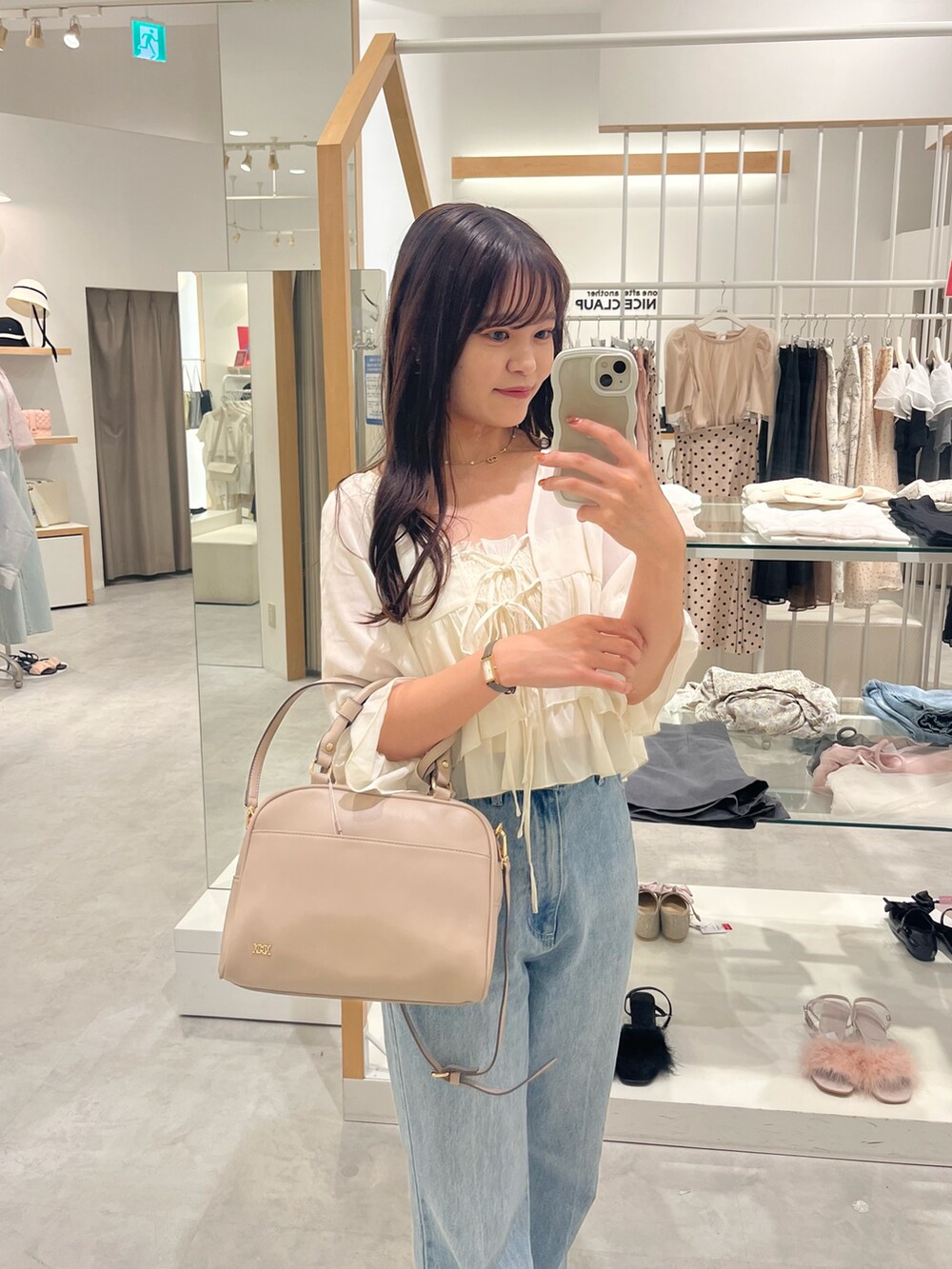 ホワイト系のボストンバッグ、ホワイト系のシャツ/ブラウス、ブルー系のデニムパンツを着用したレディースの夏コーディネートの2枚目の写真