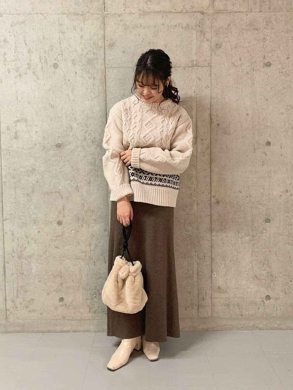 ホワイト系のニット/セーター、ブラウン系のスカート、ホワイト系のショルダーバッグを着用したレディースの冬コーディネートの2枚目の写真