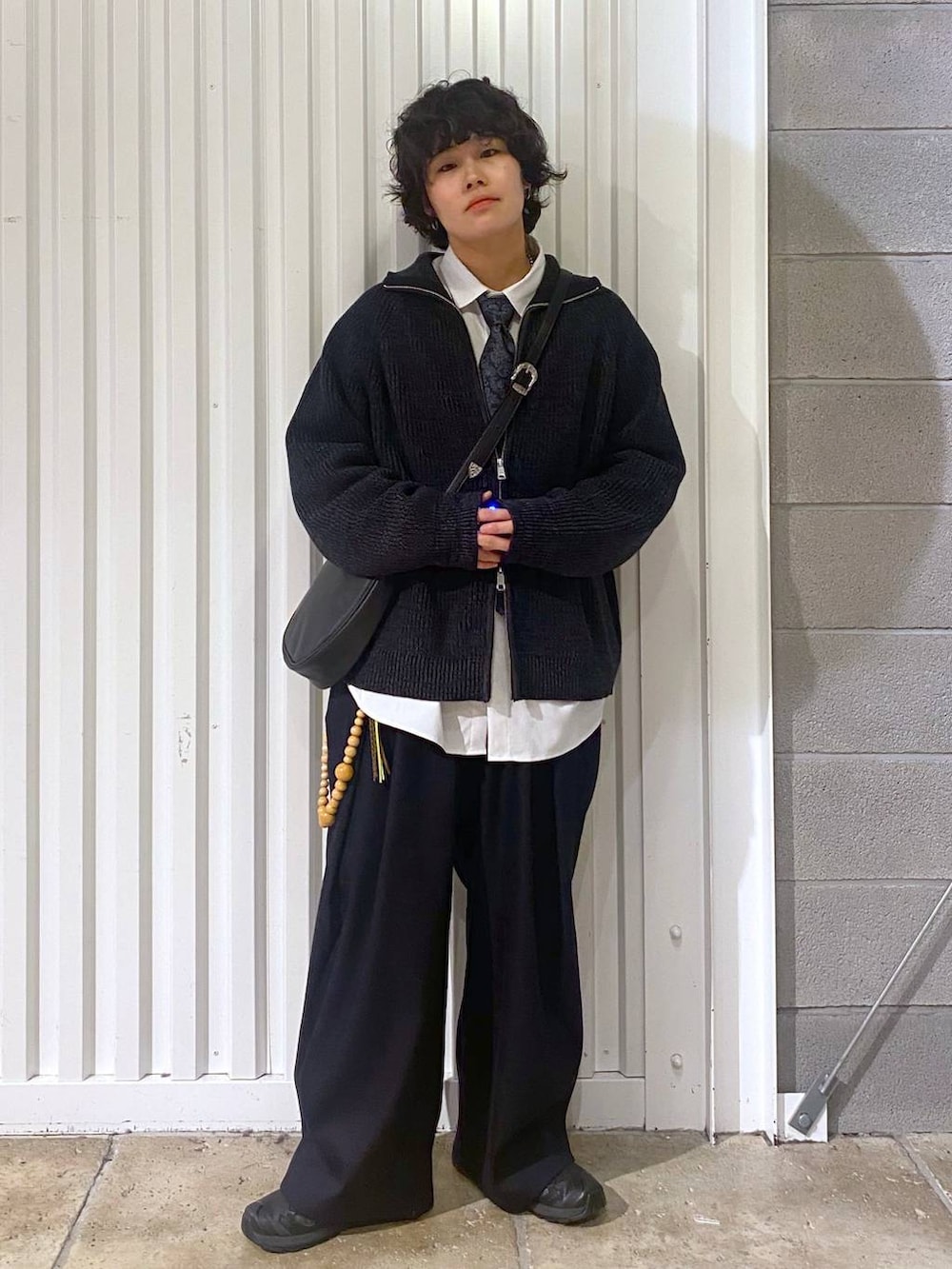 ブラック系のスニーカー、ブラック系のニット/セーター、ブラック系のショルダーバッグを着用したメンズの秋コーディネートの2枚目の写真