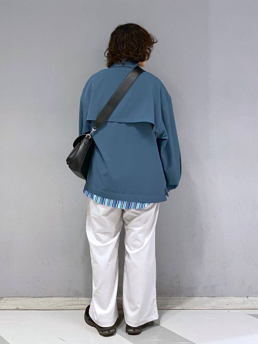ブラック系のショルダーバッグ、ホワイト系のスラックス、ブルー系のブルゾンを着用したメンズの春コーディネートの9枚目の写真