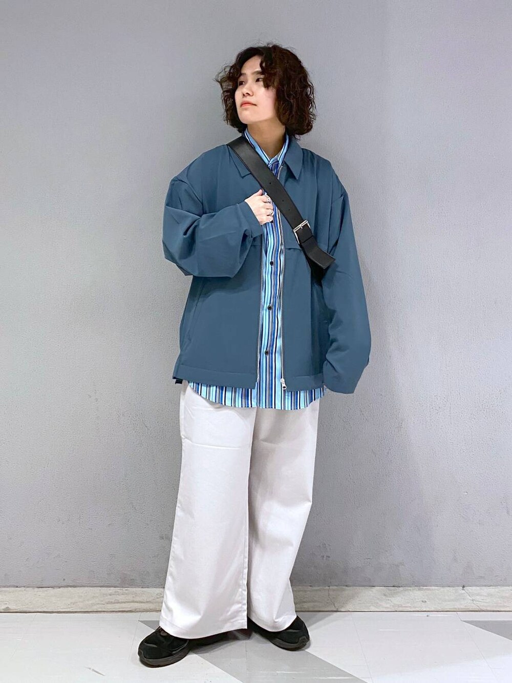 ブラック系のショルダーバッグ、ホワイト系のスラックス、ブルー系のブルゾンを着用したメンズの春コーディネートの3枚目の写真