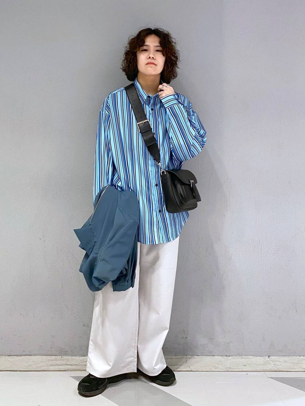 ブラック系のショルダーバッグ、ホワイト系のスラックス、ブルー系のブルゾンを着用したメンズの春コーディネートの6枚目の写真
