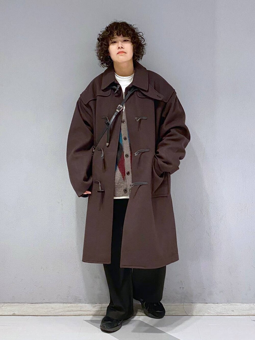 ブラウン系のダッフルコート、ブラウン系のカーディガン/ボレロ、ホワイト系のスウェットを着用したメンズの冬コーディネートの5枚目の写真