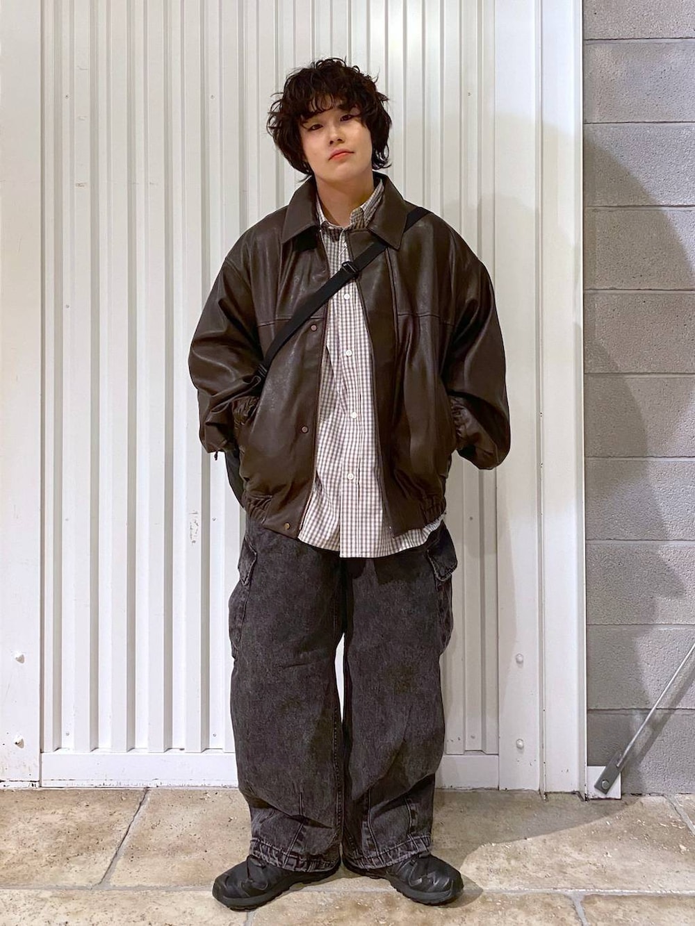 ブラック系のショルダーバッグ、ブラウン系のブルゾン、ブラック系のスニーカーを着用したメンズの秋コーディネートの6枚目の写真