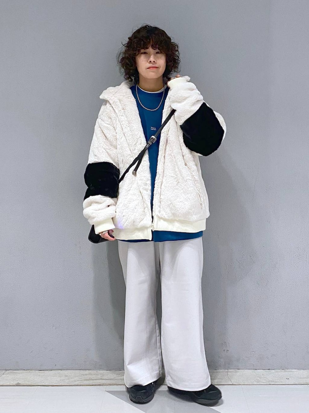 ブルー系のスウェット、ホワイト系のブルゾン、ブラック系のショルダーバッグを着用したメンズの冬コーディネートの3枚目の写真