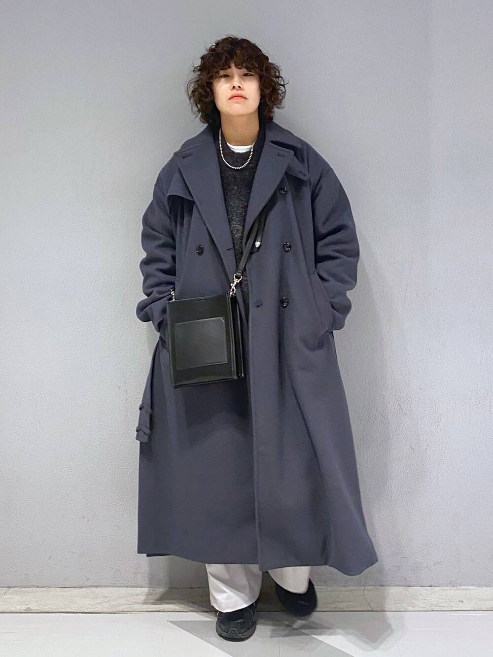 グレー系のトレンチコート、ブラック系のニット/セーター、ブラック系のショルダーバッグを着用したメンズの冬コーディネートの3枚目の写真