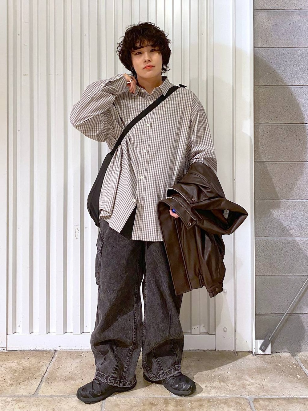 ブラック系のショルダーバッグ、ブラウン系のブルゾン、ブラック系のスニーカーを着用したメンズの秋コーディネートの2枚目の写真
