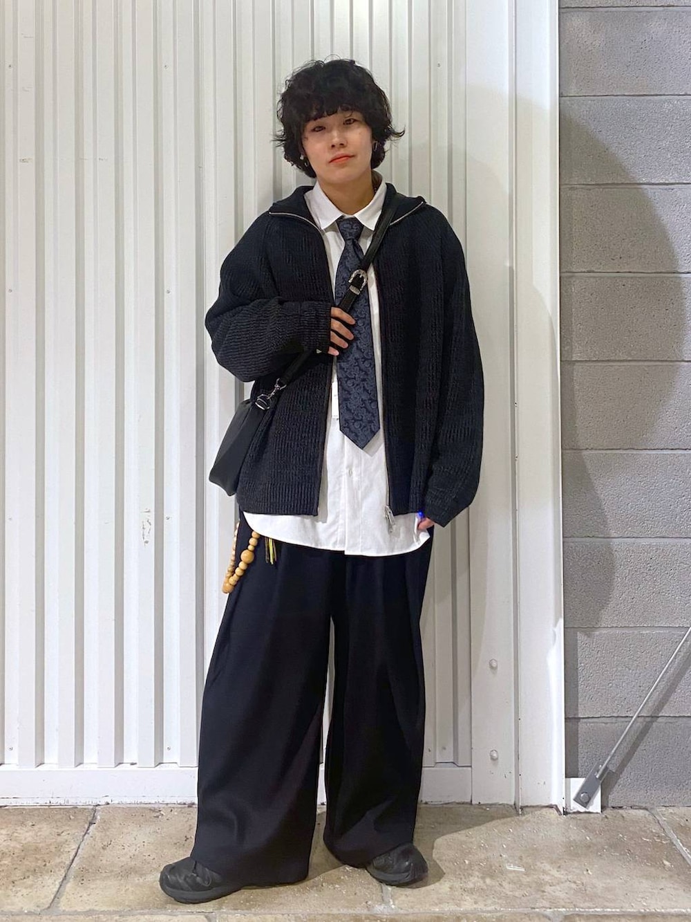 ブラック系のスニーカー、ブラック系のニット/セーター、ブラック系のショルダーバッグを着用したメンズの秋コーディネートの3枚目の写真