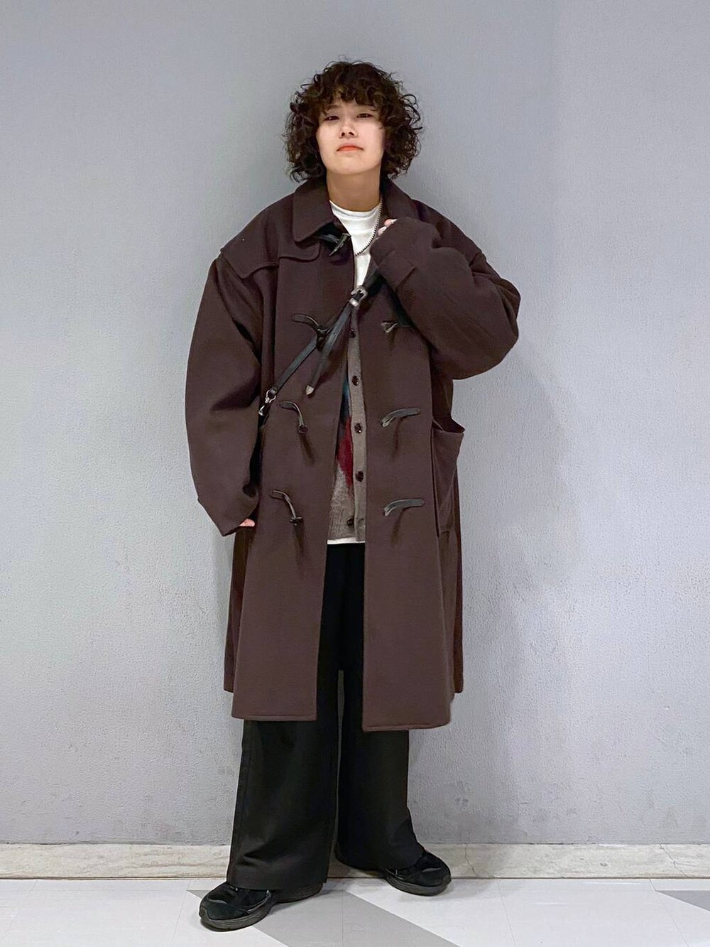 ブラウン系のダッフルコート、ブラウン系のカーディガン/ボレロ、ホワイト系のスウェットを着用したメンズの冬コーディネートの6枚目の写真