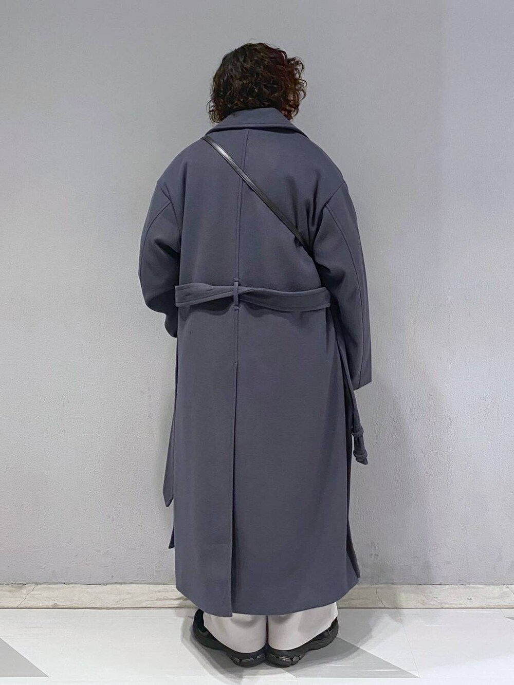 グレー系のトレンチコート、ブラック系のニット/セーター、ブラック系のショルダーバッグを着用したメンズの冬コーディネートの9枚目の写真