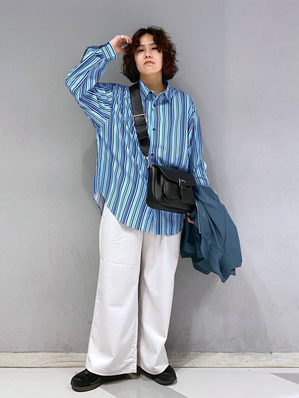 ブラック系のショルダーバッグ、ホワイト系のスラックス、ブルー系のブルゾンを着用したメンズの春コーディネートの5枚目の写真