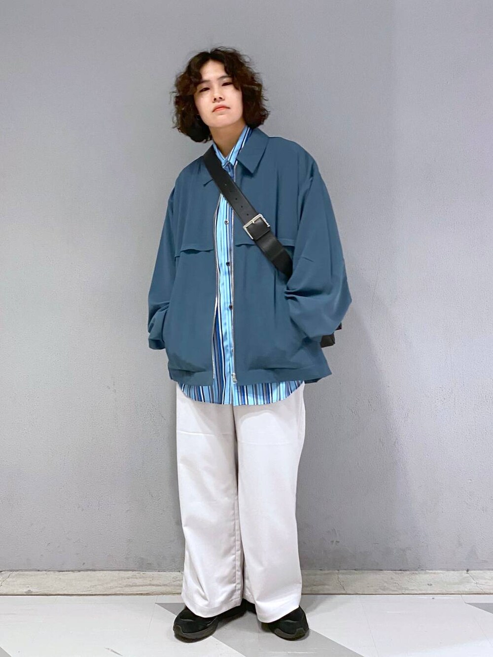 ブラック系のショルダーバッグ、ホワイト系のスラックス、ブルー系のブルゾンを着用したメンズの春コーディネートの4枚目の写真