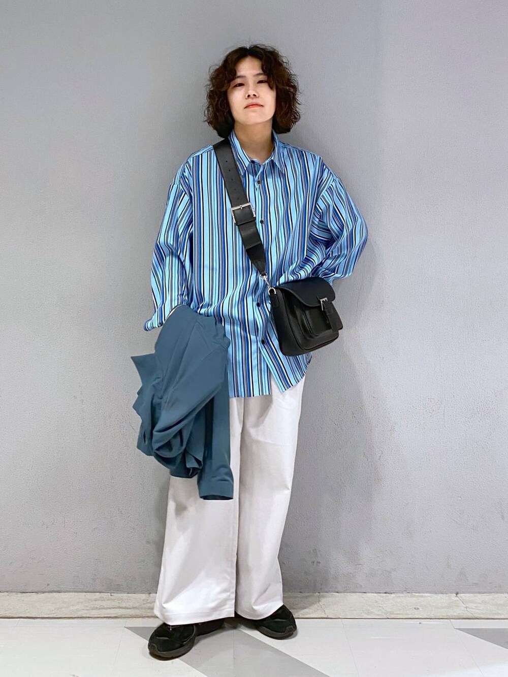 ブラック系のショルダーバッグ、ホワイト系のスラックス、ブルー系のブルゾンを着用したメンズの春コーディネートの7枚目の写真