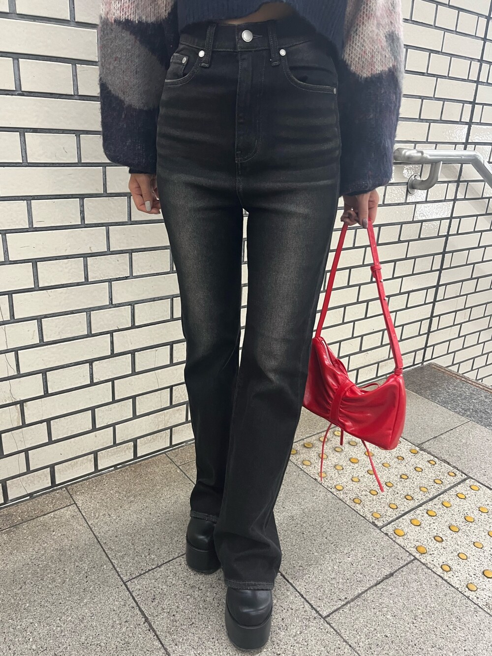 ブラック系のデニムパンツ、ブルー系のニット/セーター、レッド系のショルダーバッグを着用したレディースの秋コーディネートの8枚目の写真