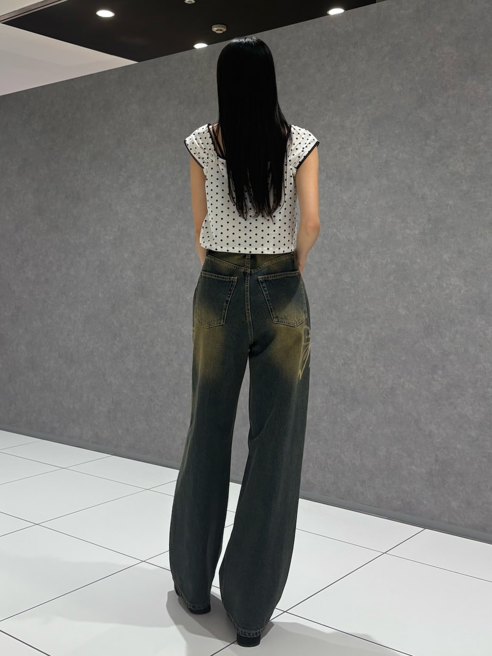 ホワイト系のタンクトップ、ブルー系のデニムパンツ、ブラック系のサンダルを着用したレディースの夏コーディネートの3枚目の写真