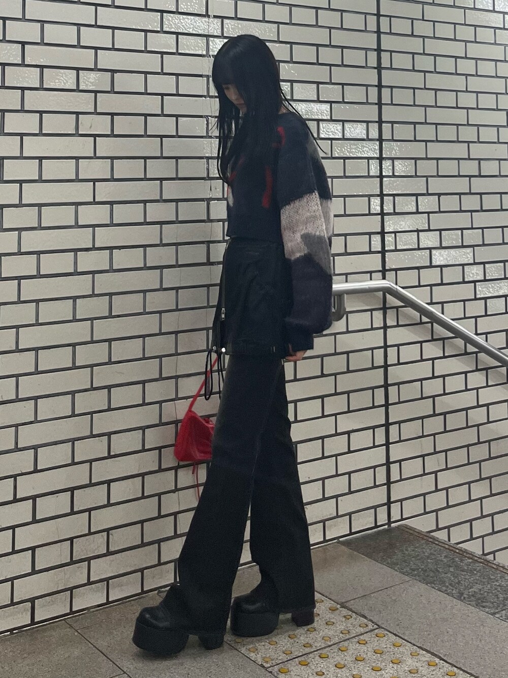 ブラック系のデニムパンツ、ブルー系のニット/セーター、レッド系のショルダーバッグを着用したレディースの秋コーディネートの2枚目の写真