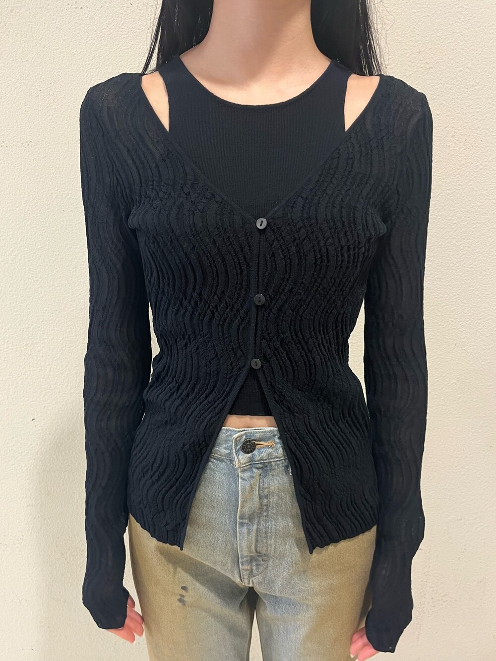 ブラック系のニット/セーター、ブルー系のデニムパンツ、ブラック系のサンダルを着用したレディースの春コーディネートの5枚目の写真