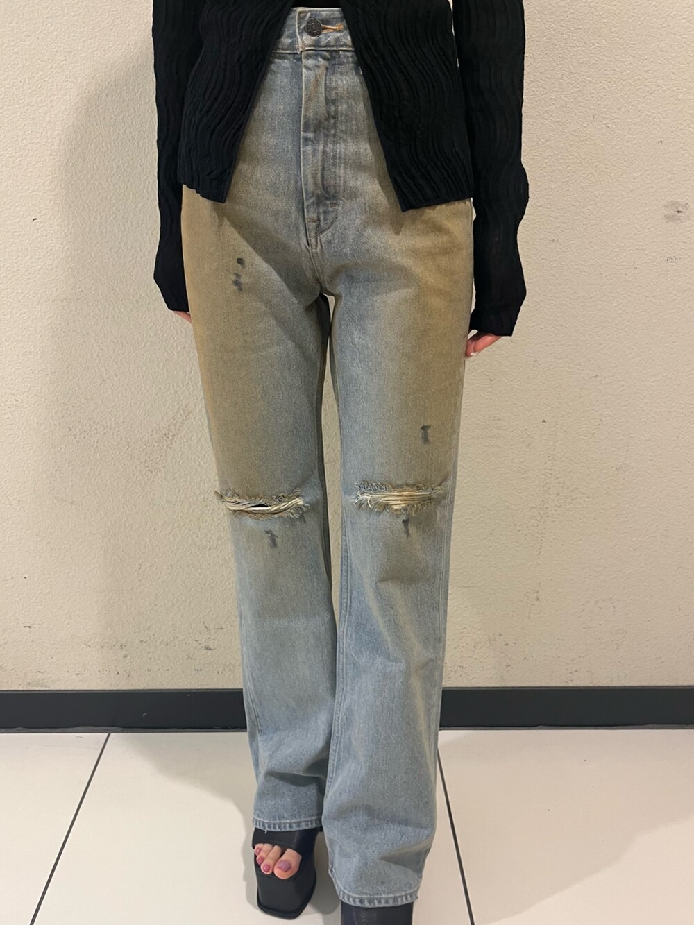 ブラック系のニット/セーター、ブルー系のデニムパンツ、ブラック系のサンダルを着用したレディースの春コーディネートの6枚目の写真