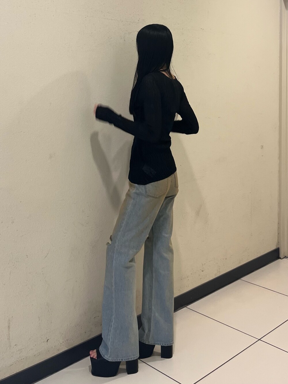 ブラック系のニット/セーター、ブルー系のデニムパンツ、ブラック系のサンダルを着用したレディースの春コーディネートの2枚目の写真