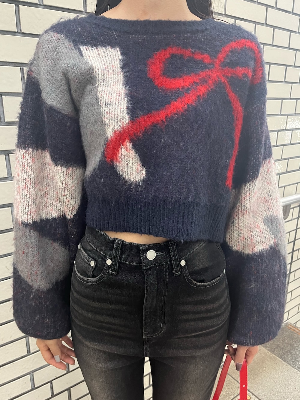 ブラック系のデニムパンツ、ブルー系のニット/セーター、レッド系のショルダーバッグを着用したレディースの秋コーディネートの6枚目の写真