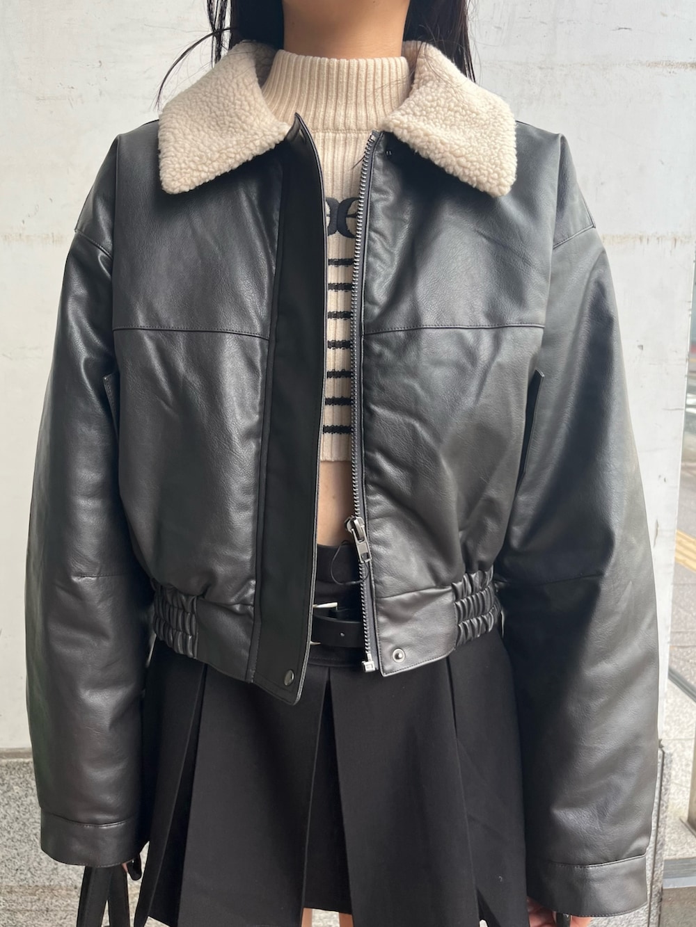 グレー系のブルゾン、ホワイト系のニット/セーター、ブラック系のスカートを着用したレディースの秋コーディネートの5枚目の写真