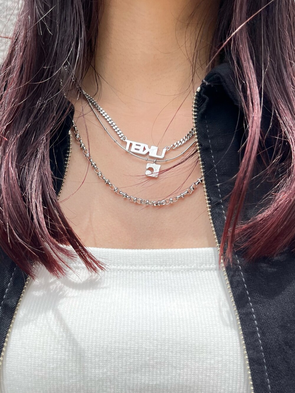 シルバー系のハンドバッグ、ブラック系のデニムスカート、ホワイト系のキャミソールを着用したレディースの夏コーディネートの9枚目の写真